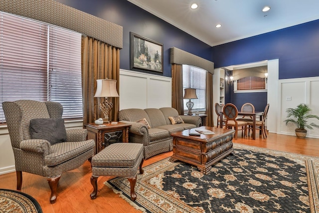 living room with built in shelves, a healthy amount of sunlight, ornamental molding, and hardwood / wood-style flooring