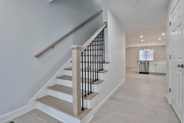 stairs featuring hardwood / wood-style flooring and an inviting chandelier