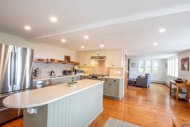 kitchen featuring sink, light hardwood / wood-style flooring, decorative backsplash, appliances with stainless steel finishes, and a kitchen island