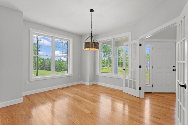 unfurnished dining area with light hardwood / wood-style floors and an inviting chandelier