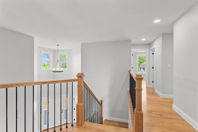 hall with a notable chandelier and light hardwood / wood-style flooring