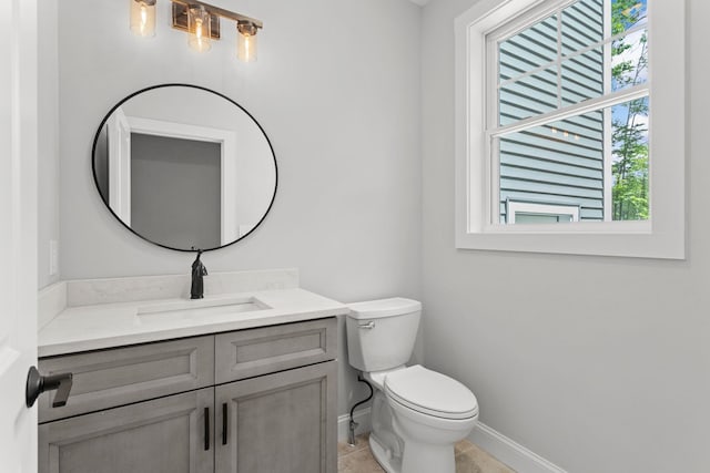 bathroom with tile patterned flooring, vanity, toilet, and a wealth of natural light