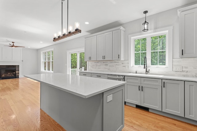 kitchen with backsplash, gray cabinets, sink, and hanging light fixtures