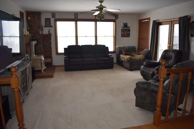 carpeted living room featuring ceiling fan and a wood stove