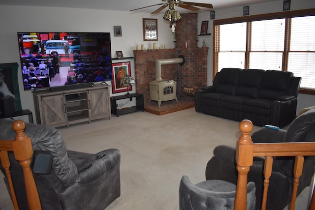 carpeted living room with ceiling fan, a wood stove, and a healthy amount of sunlight