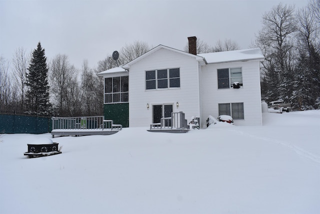 snow covered rear of property featuring a sunroom and central air condition unit