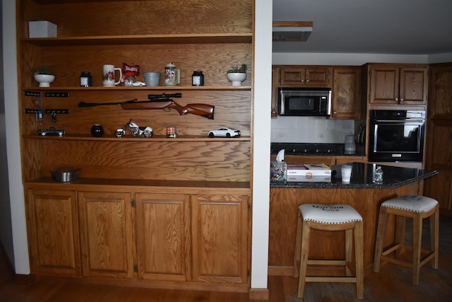 interior space with dark hardwood / wood-style flooring, tasteful backsplash, black oven, and dark stone counters