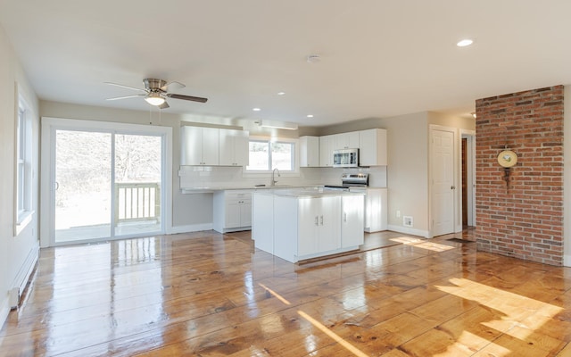 kitchen with white cabinetry, a center island, sink, decorative backsplash, and appliances with stainless steel finishes