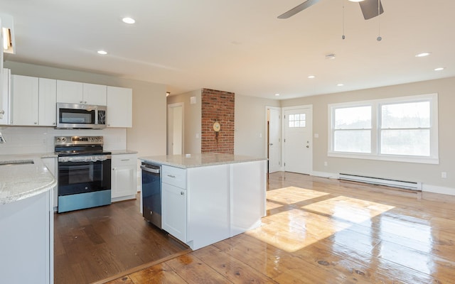 kitchen with a kitchen island, white cabinetry, stainless steel appliances, and a baseboard heating unit