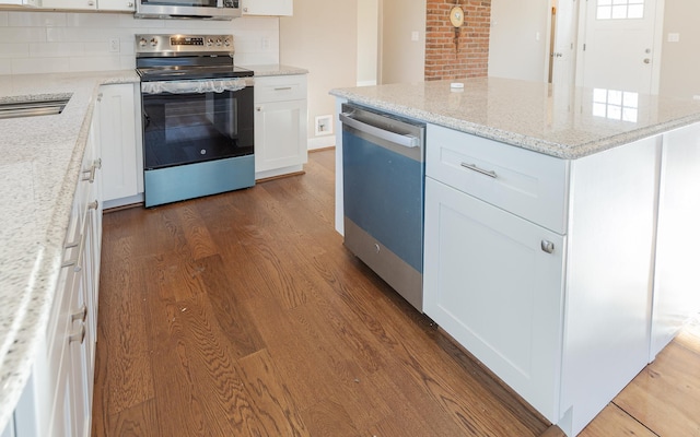 kitchen featuring light stone countertops, tasteful backsplash, stainless steel appliances, dark wood-type flooring, and white cabinets