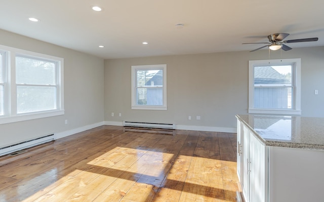 interior space with baseboard heating, a wealth of natural light, and light wood-type flooring