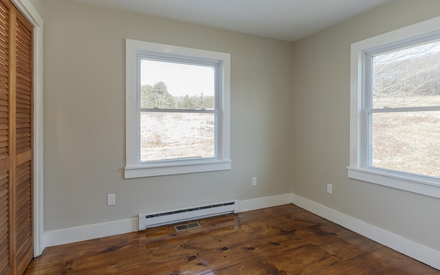 unfurnished room with dark hardwood / wood-style floors, baseboard heating, and a healthy amount of sunlight