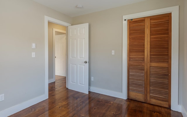 unfurnished bedroom with a closet and dark wood-type flooring