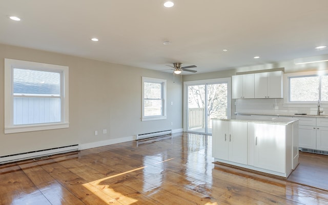 kitchen with baseboard heating, ceiling fan, light hardwood / wood-style flooring, and white cabinets