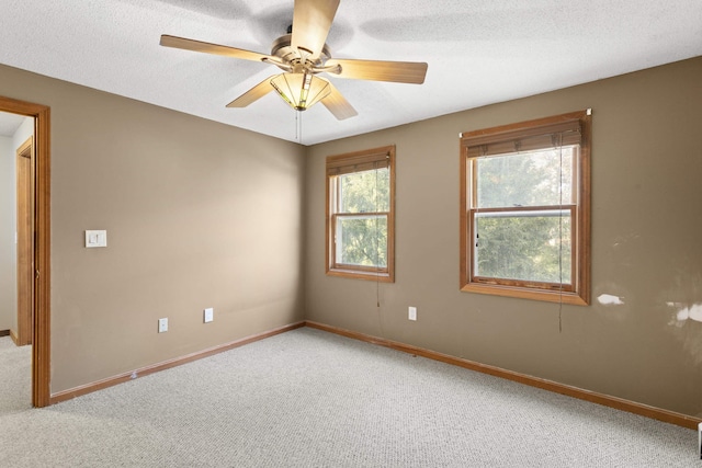 unfurnished room featuring carpet flooring, ceiling fan, a healthy amount of sunlight, and a textured ceiling