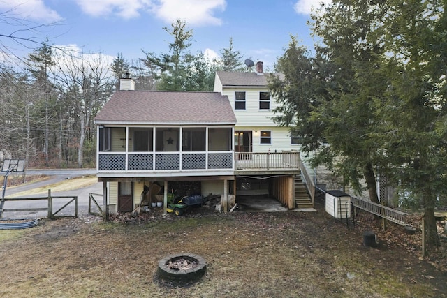 back of property featuring a sunroom, an outdoor fire pit, and a wooden deck