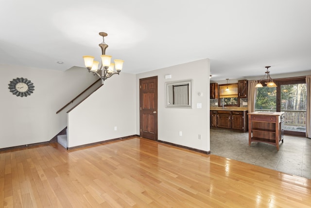 unfurnished living room featuring light wood-type flooring and an inviting chandelier