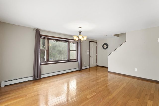 empty room featuring light hardwood / wood-style floors, an inviting chandelier, and a baseboard heating unit