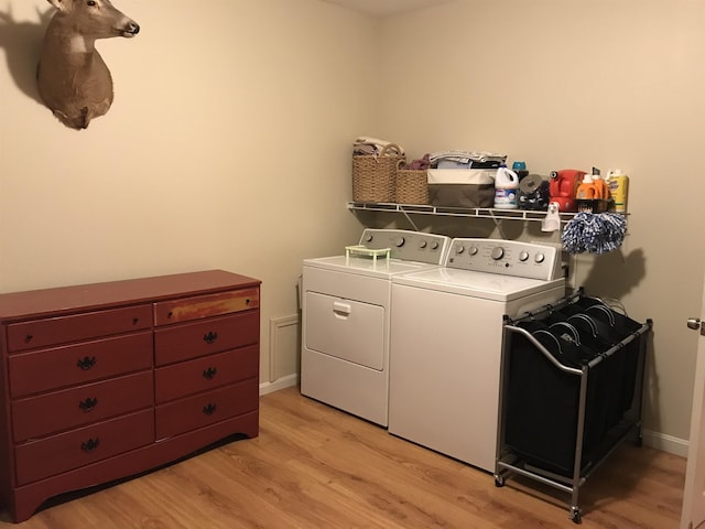 clothes washing area with light hardwood / wood-style flooring and washer and dryer