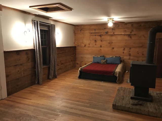 bedroom featuring hardwood / wood-style flooring, crown molding, a wood stove, and wooden walls