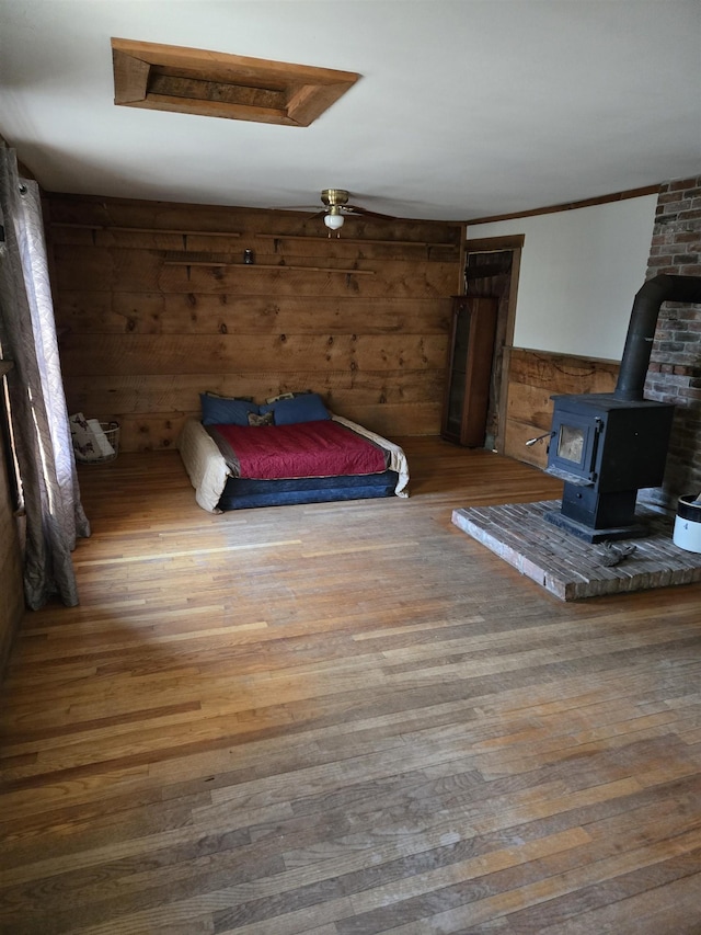 unfurnished bedroom featuring a wood stove and hardwood / wood-style flooring