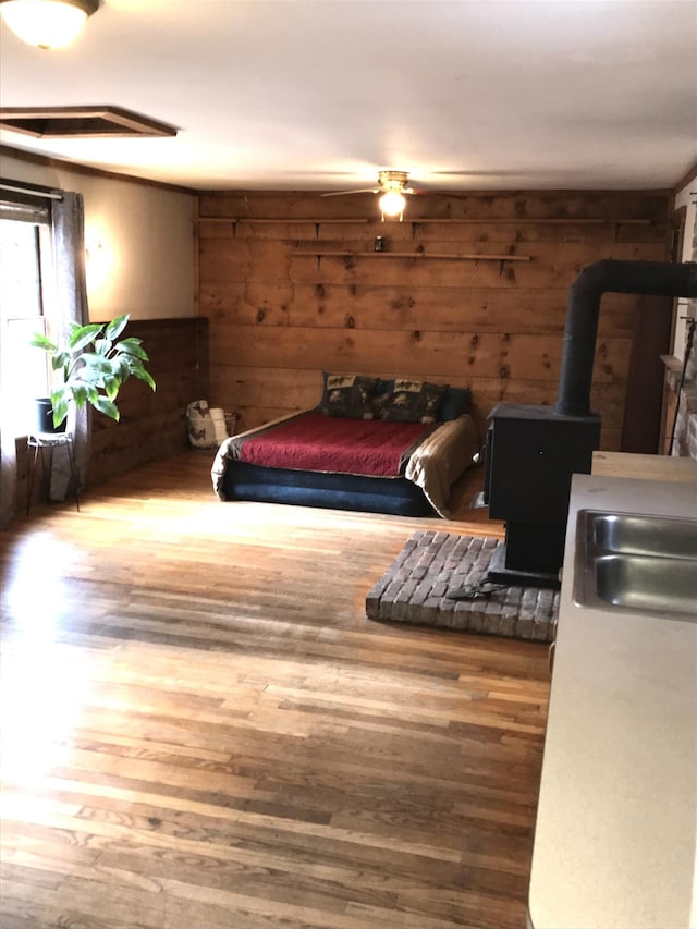 bedroom featuring a wood stove, hardwood / wood-style floors, and wooden walls