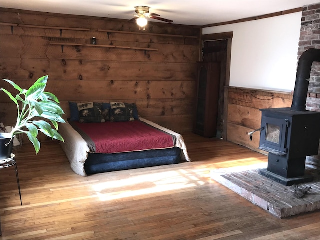 bedroom with a wood stove, wood-type flooring, and wood walls