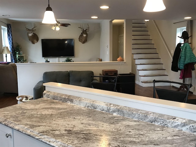 interior space with ceiling fan, dark wood-type flooring, white cabinetry, and hanging light fixtures