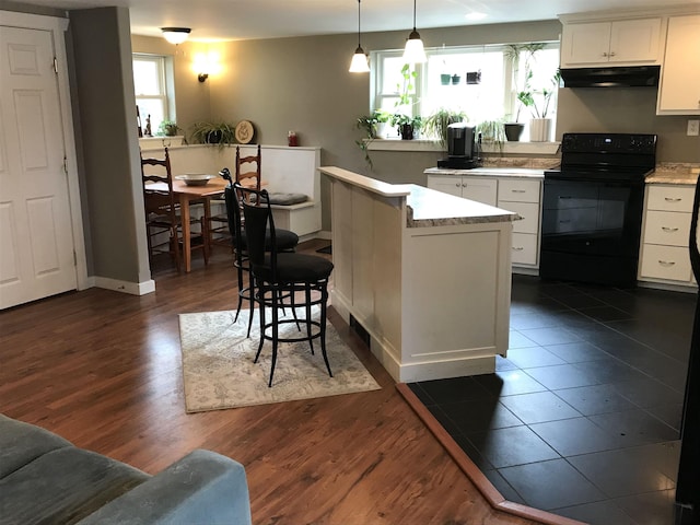 kitchen featuring white cabinetry, electric range, hanging light fixtures, a kitchen island, and a breakfast bar area