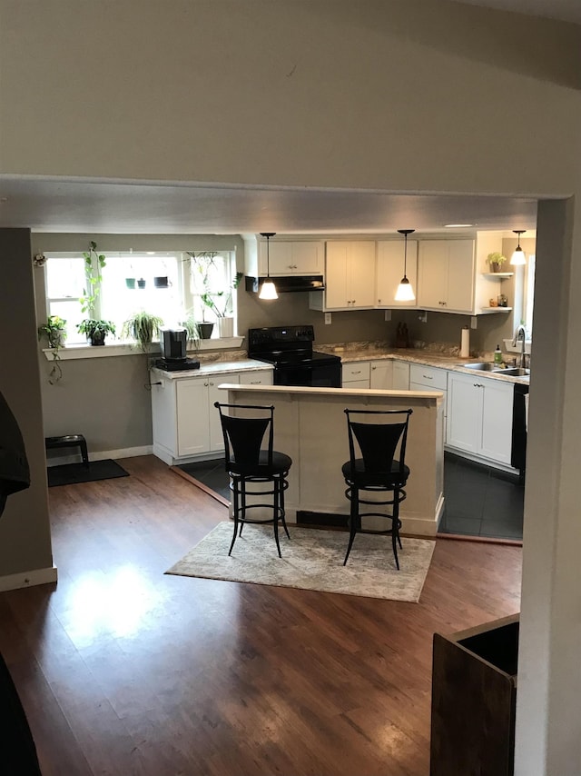 kitchen featuring white cabinets, black / electric stove, sink, and decorative light fixtures