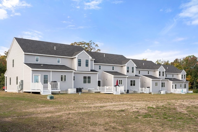 rear view of property featuring central AC unit, a lawn, and a wooden deck