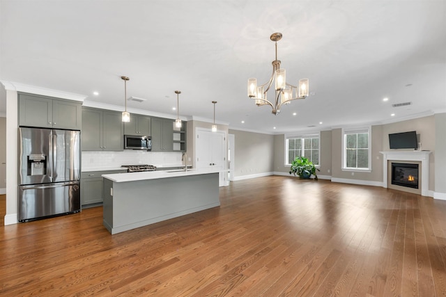 kitchen featuring pendant lighting, sink, gray cabinets, an island with sink, and appliances with stainless steel finishes