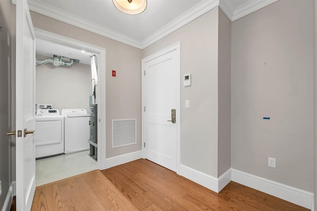 foyer entrance featuring separate washer and dryer, crown molding, and light hardwood / wood-style flooring