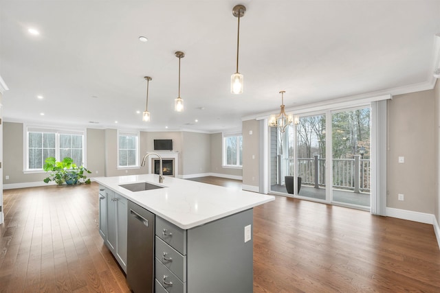 kitchen with pendant lighting, gray cabinetry, a center island with sink, sink, and stainless steel dishwasher