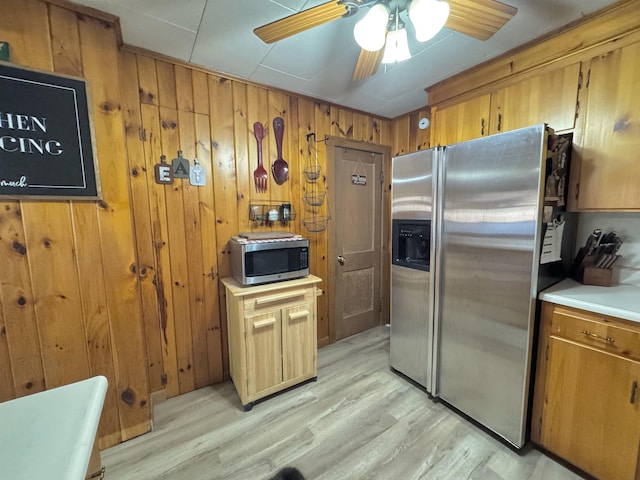 kitchen featuring appliances with stainless steel finishes, light hardwood / wood-style floors, and wood walls