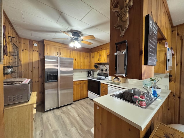 kitchen featuring white appliances, wooden walls, ceiling fan, light hardwood / wood-style floors, and kitchen peninsula