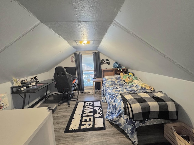 bedroom featuring a textured ceiling, hardwood / wood-style floors, and vaulted ceiling