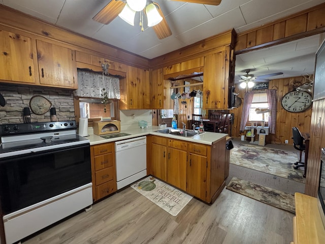 kitchen with kitchen peninsula, sink, white appliances, and light hardwood / wood-style flooring