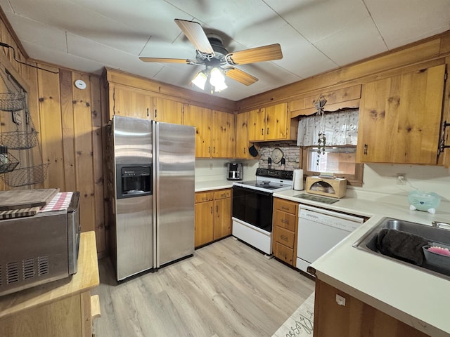 kitchen featuring ceiling fan, sink, light hardwood / wood-style floors, white appliances, and wooden walls