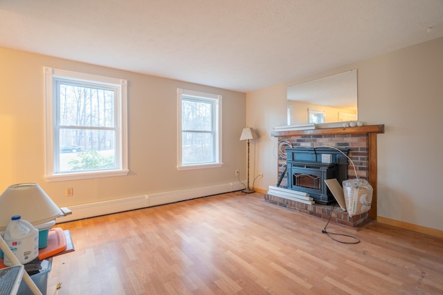 sitting room with light wood-type flooring, a wood stove, and a baseboard heating unit