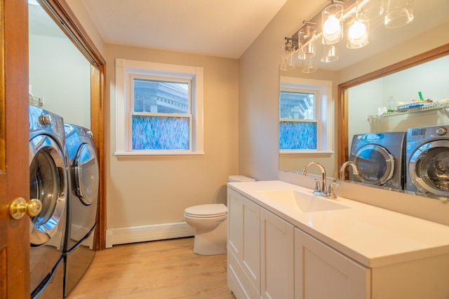 bathroom featuring vanity, baseboard heating, hardwood / wood-style floors, washing machine and dryer, and toilet