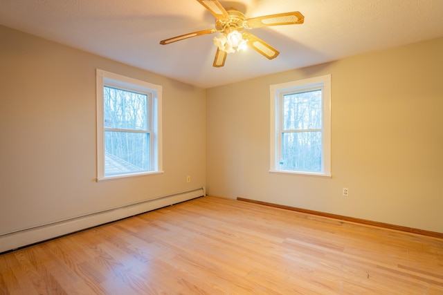 spare room featuring baseboard heating, ceiling fan, and light wood-type flooring