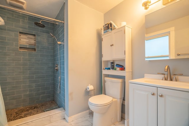 bathroom with tiled shower, vanity, and toilet