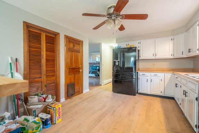 kitchen with white cabinetry, black fridge, ceiling fan, and light hardwood / wood-style flooring