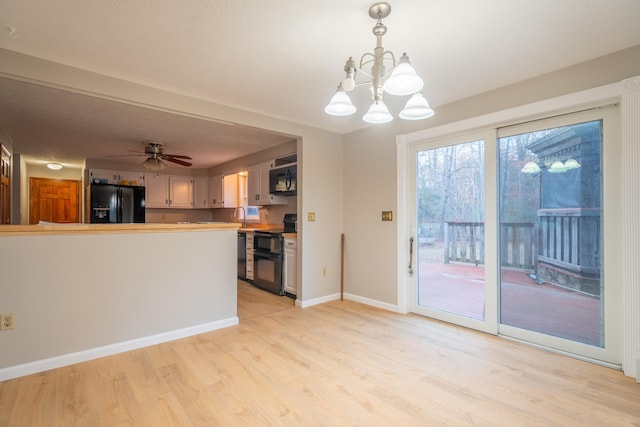 kitchen with light hardwood / wood-style flooring, kitchen peninsula, pendant lighting, black appliances, and ceiling fan with notable chandelier