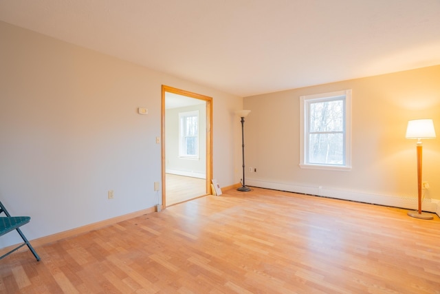 unfurnished room with baseboard heating and light hardwood / wood-style flooring