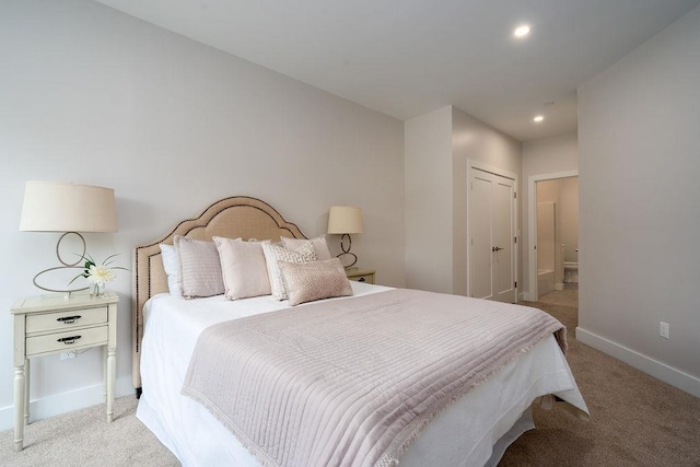 bedroom with light carpet, ensuite bath, and a closet