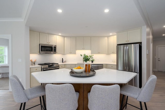 kitchen featuring a center island, white cabinets, stainless steel appliances, and light wood-type flooring