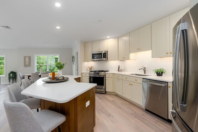 kitchen featuring sink, appliances with stainless steel finishes, a breakfast bar, a kitchen island, and light wood-type flooring