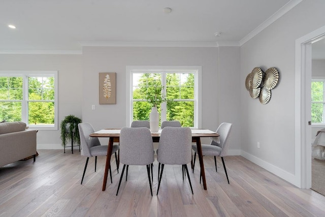 dining space with a healthy amount of sunlight, ornamental molding, and light hardwood / wood-style flooring